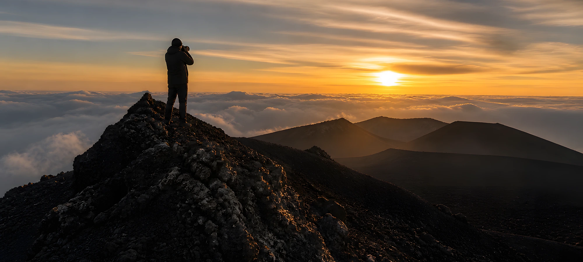 L'ultima luce del giorno dal cratere, un escursionista fotografa il tramonto