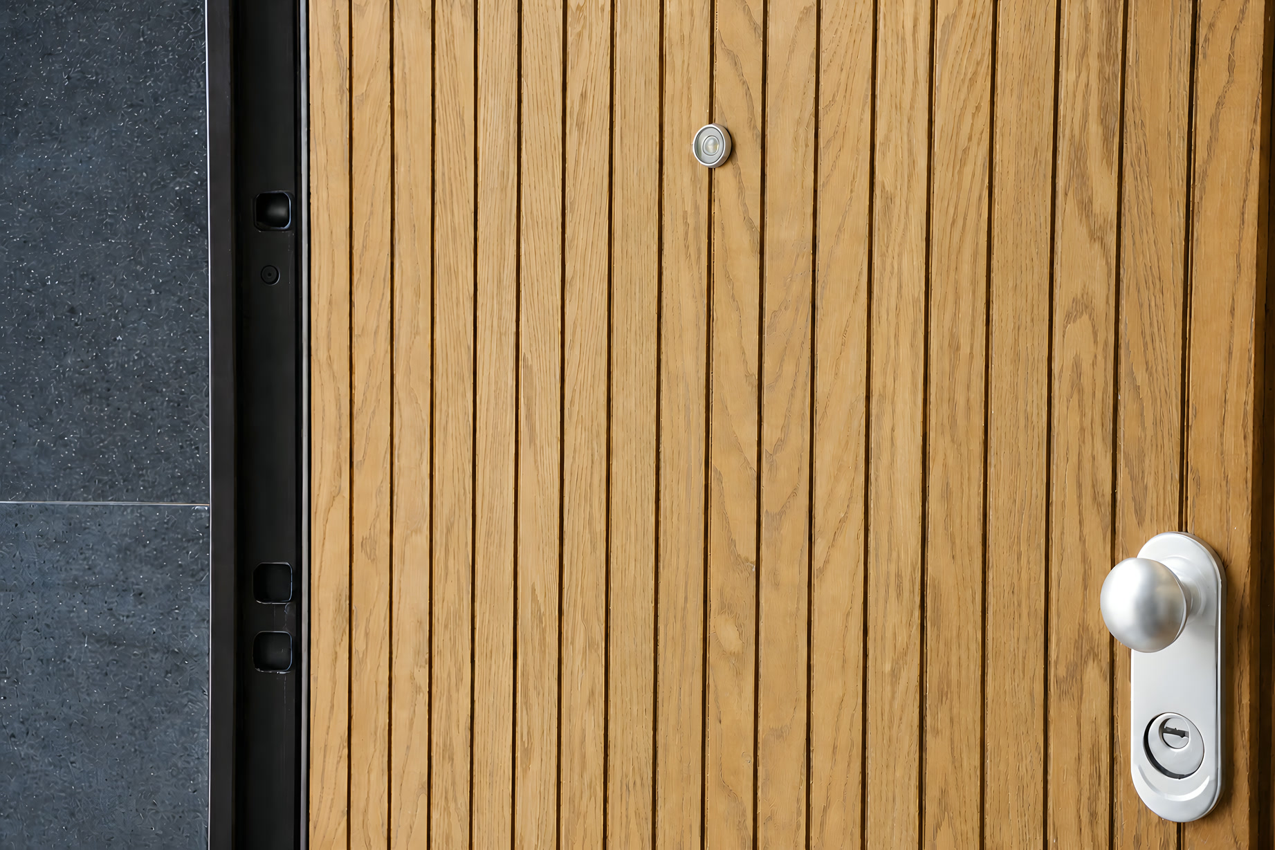 La porta d’ingresso a doghe di legno, con la maniglia in acciaio