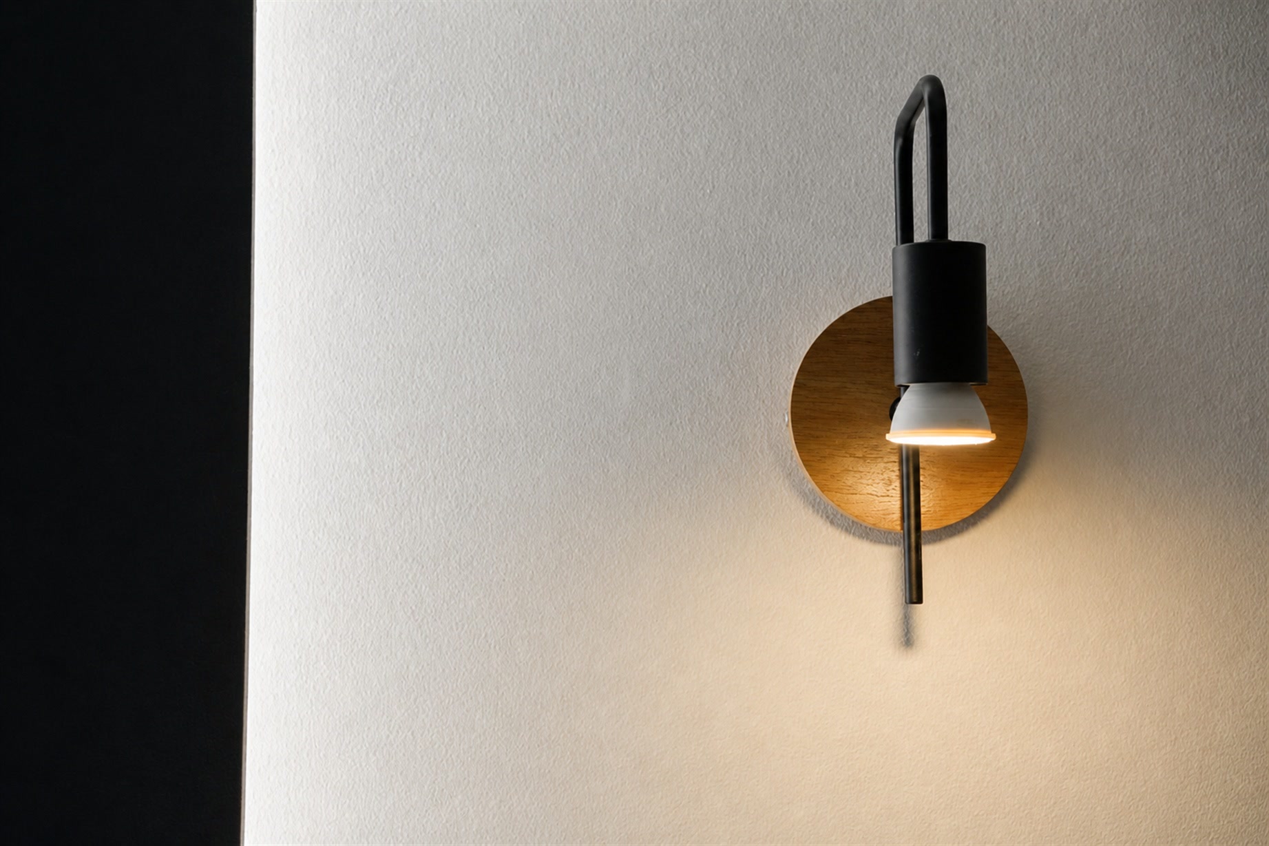 Applique nera su disco di legno, luce calda