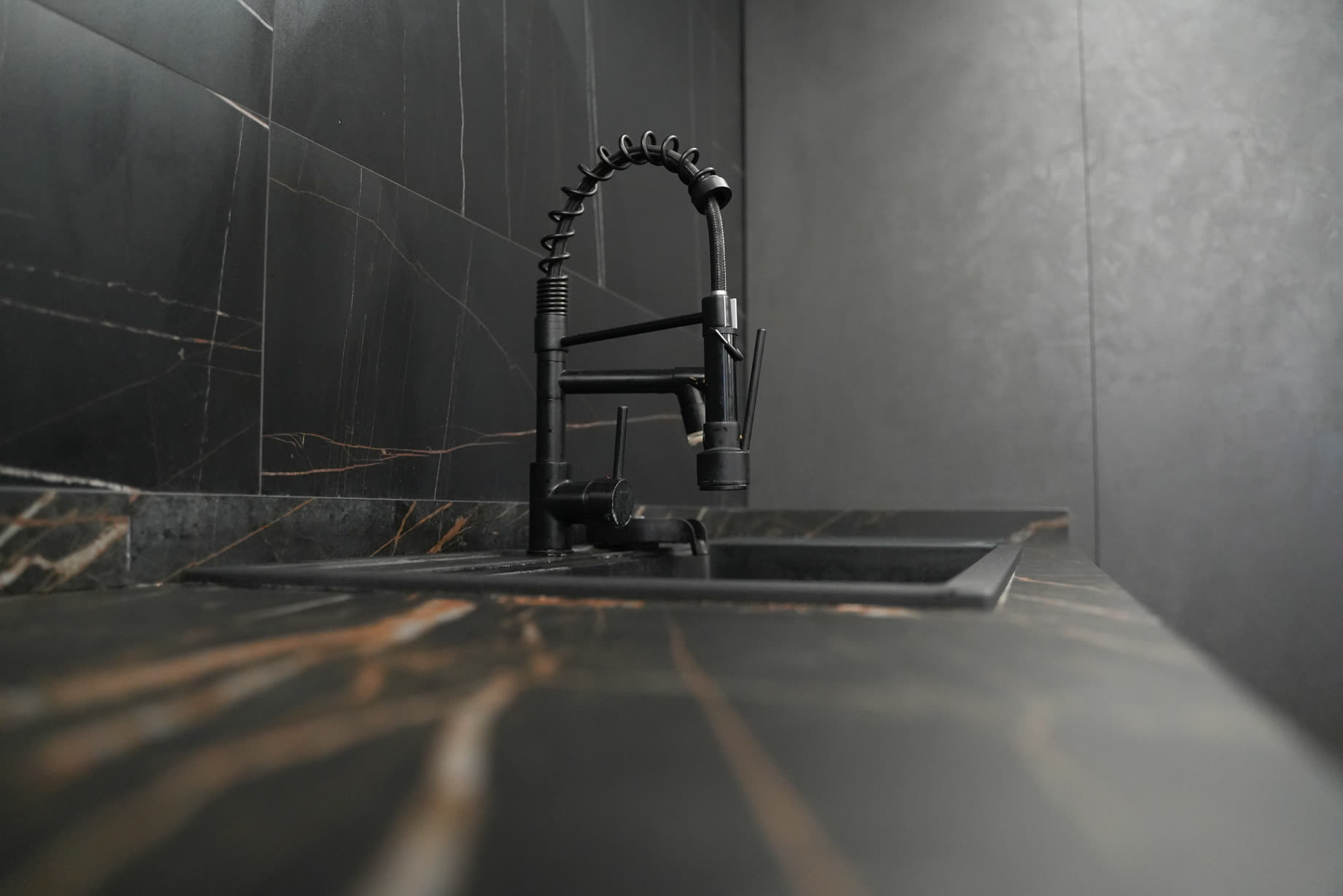 Rubinetto nero su piano cucina in marmo nero con venature dorate