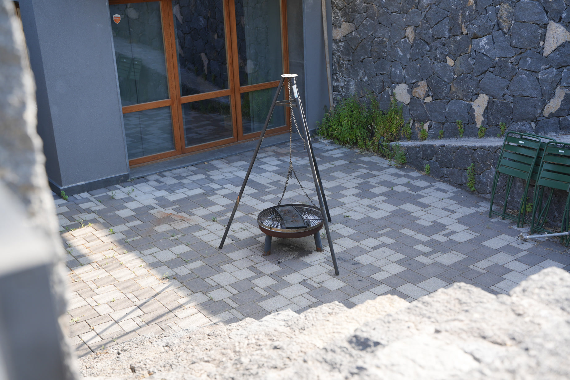 Il patio pavimentato con braciere in ferro, tra muri di pietra lavica