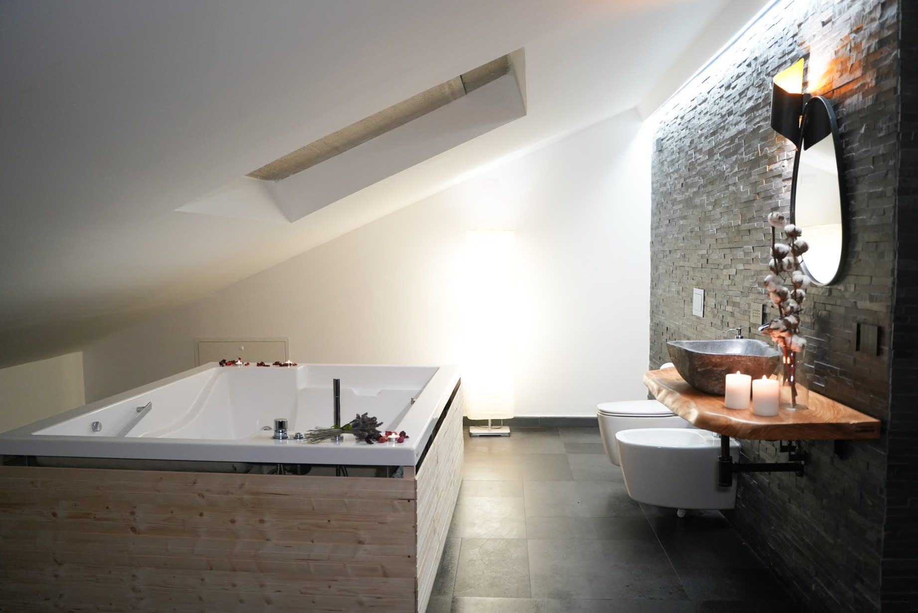Suite spa: vasca idromassaggio incassata davanti al muro in pietra, luce calda soffusa